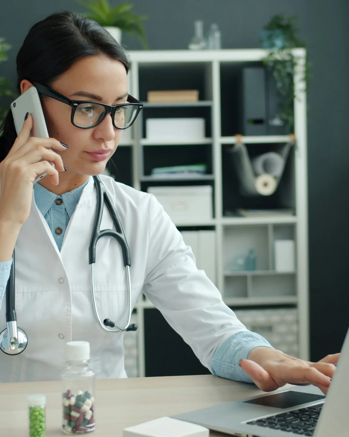 Professionista sanitaria al telefono mentre lavora al computer
